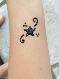 a small tattoo on the arm of a person with a star and swirls around it