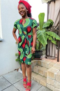 a woman standing in front of a house wearing a green and red dress