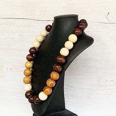 This colorful wood bead necklace was hand beaded using a mix of large 25mm round dark brown, tan, and beige wooden beads in a modern color block design. The necklace measures approximately 28 inches in length and is fastened with a silver clasp. The end result is a cool bohemian piece that fits in perfectly with almost any outfit! Perfect for any gender. Length can be adjusted if needed - just ask! Wood represents a sense of earthiness, spirituality, creativity, liberty, prosperity, health, and Adjustable Brown Round Beaded Necklace, Adjustable Round Brown Beaded Necklace, Adjustable Brown Beaded Round Necklace, Adjustable Brown Beaded Necklace, Brown Wooden Beads Round Jewelry, Brown Wooden Beads Jewelry, Brown Round Wooden Beads Jewelry, Handmade Brown Round Beaded Necklaces, Handmade Brown Beaded Necklaces