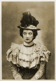 an old black and white photo of a woman wearing a hat with feathers on it