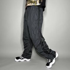 "Vintage Starter Track Pants Dark Grey Polyester Sweatpants Subtle Embroidered Logo Baggy Fit has Ankle Zippers Lined 90s Skate / Streetwear Great Condition: 9/10 Men's Size: Large My Hands in Pockets = It has Pockets No Hands in Pockets = Does Not Have Pockets Drawstring Will be Visible in Forward Pic, if not Visible it Does Not Have a Drawstring About me: I am 6' 0\" for reference I generally wear a Large (32\" inseam) I Model XS to 2XL sweatpants, I find that you can often size up or down with 95% of sweatpants and they fit the same" 90s Wide Leg Parachute Pants For Streetwear, 90s Baggy Parachute Trousers, 90s Style Baggy Parachute Trousers, 90s Style Cargo Pants For Streetwear, 90s Parachute Pants For Streetwear, 90s Streetwear Trousers, 90s Style Streetwear Trousers, Relaxed Fit Casual Cargo Pants With Zip Fly, 90s Style Full-length Streetwear Pants