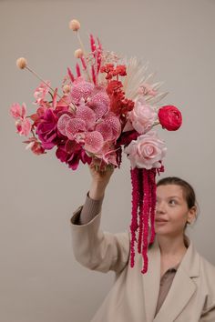 a woman holding a bouquet of flowers in front of her face and looking up at the sky