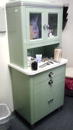 a green cabinet sitting on top of a carpeted floor