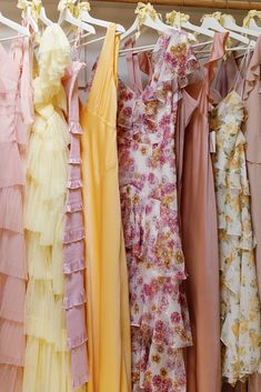 several dresses hanging on a clothes line with flowers and ruffles all over them