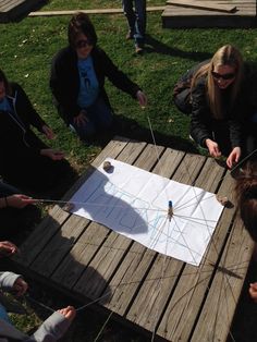 several people sitting around a wooden table with a kite on it and one person holding a string