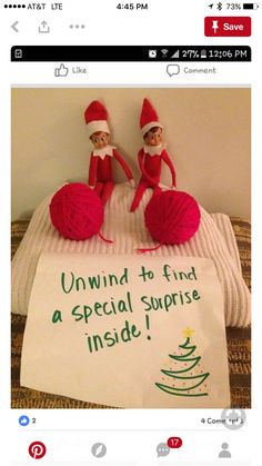 two elfs sitting on top of a bed next to a sign that says, unwind to find a special surprise inside