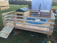 a dog house made out of pallets and wooden boards with a pool in the middle