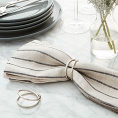 a table topped with plates and silverware next to a striped bow tie napkin holder