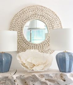 two lamps sitting on top of a white mantle next to a mirror and lamp shade