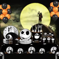 a table topped with lots of halloween themed plates and balloons in front of a full moon