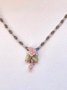 Colleen Toland Vintage inspired Flower Garden Necklace and Pendant Set with dainty flowers and leaves that are hand colored here in our studio.  The colors are pastel in soft pink green and lavender. They are beaded together with glass seed beads and finished with pretty glass drops.  The necklace chain is handbeaded with tiny seed beads. The necklace closure is a hook and there is a 4 inch extender so as the length can be adjusted.  There is a metal tag with Colleens name on it. The earrings ar Necklace Closure, Dainty Flowers, Metal Tag, Metal Tags, Beaded Pendant Necklace, Floral Necklace, Necklace And Earring Set, Flower Pendant, Necklace Chain