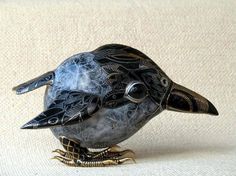 a decorative black bird sitting on top of a white cloth covered floor next to a wall