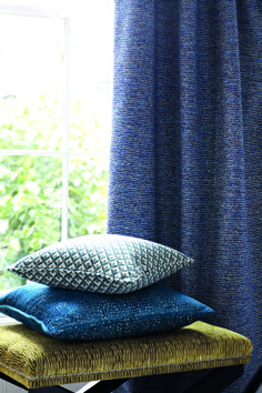 three pillows stacked on top of each other in front of a window with blue curtains