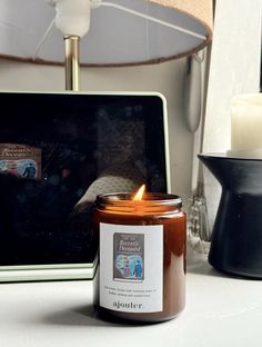 a candle sitting on top of a table next to a laptop