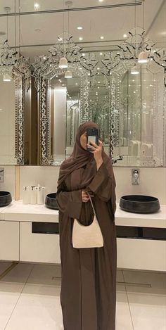 a woman taking a selfie in front of a bathroom mirror while holding a cell phone