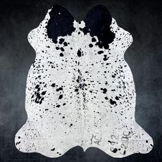 a black and white spotted cowhide rug on a dark background with some writing underneath it