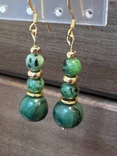 Introducing our exquisite handmade jade green beaded dangle earrings, designed to add a touch of elegance to any outfit. Each earring features stunning jade green beads, carefully paired with pretty gold-tone alloy metal beads for a sophisticated contrast. The gold-plated settings enhance the overall luxurious feel, making these earrings perfect for both casual and formal occasions. Treat yourself or a loved one to these timeless beauties that effortlessly blend classic charm with modern style.  Check out the matching bracelets that are listed separately. Adjustable Round Beads Jade Earrings, Adjustable Jade Earrings With Ear Wire, Adjustable Jade Jewelry With Ear Wire, Jade Dangle Earrings For Pierced Ears, Aventurine Dangle Earrings For Gift, Aventurine Drop Earrings For Gift, Nickel-free Green Jade Jewelry, Green Jade Earrings For Pierced Ears, Handmade Jade Teardrop Earrings