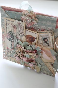 a close up of an open book with pictures and flowers on the inside, sitting on a table