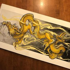 a drawing of two yellow dragon sitting on top of a wooden table