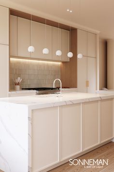 a kitchen with marble counter tops and white cabinets, along with hanging lights above the island