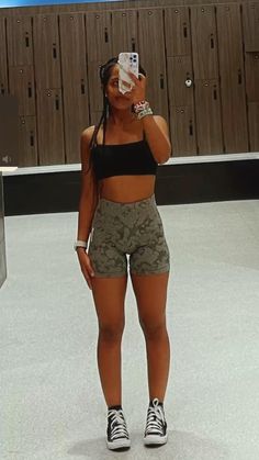 a woman standing in front of a locker room holding a cell phone up to her face