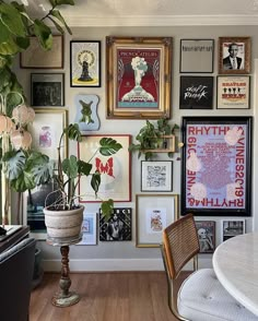 a room filled with lots of framed pictures and potted plants next to a piano