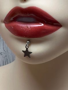 a close up shot of a woman's face with red lipstick and black star earrings