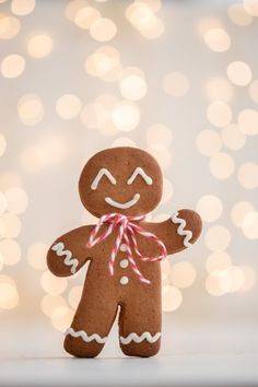 a close up of a gingerbread man on a white surface with lights in the background