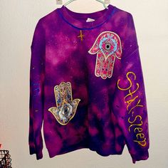 My Daughter Made This Sweatshirt! At No Additional Cost If You Want She Said She Will Add Rhinestones To The Yellow Cross On The Neck Area - The Rhinestones Will Be Clear & They Will Stay On. We Have The Ones For Fabric With Fabric Glue. And On The Back, It Just Has The Hamsa Hand The Arms Say Wake Up, Stay Sleep On Each Arm And Blue And Yellow. She Wants To Put Something In Either Fabric Paint Or The Glitter Letters. If We Did The Glitter Letters I Think It Would Be Cute She Said She Would Make Purple Relaxed Fit Sweatshirt With Graphic Print, Purple Relaxed Fit Graphic Print Sweatshirt, Purple Crew Neck Sweatshirt With Graphic Print, Purple Graphic Print Crew Neck Sweatshirt, Purple Relaxed Fit Long Sleeve T-shirt, Carhartt Hoodie Woman, Camo Sweater, Carhartt Hoodie, Pink Crewneck Sweatshirt