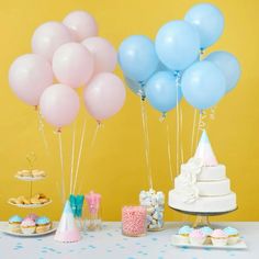 a table topped with cake and balloons next to cupcakes on top of plates