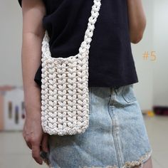 a woman is holding a crocheted purse in her left hand and wearing a black shirt