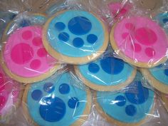 some cookies with blue and pink icing are in plastic wrappers on a table