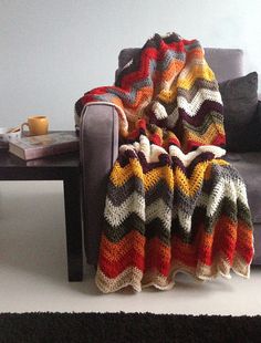 a crocheted blanket sitting on top of a couch next to a coffee table