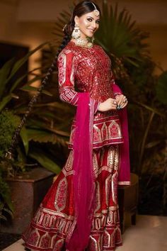 a woman in a red and gold outfit standing next to some potted plantes