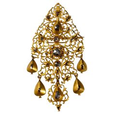 Antique diamond sequile pendant/brooch in 19.2kt yellow gold, Portugal, early 18th century. This Portuguese jewel from the Georgian period of an intricately pierced openwork "sequilé” design is richly accented throughout with 31 rose-cut and table-cut diamonds, the yellow gold embellished with profuse chiseled and scalloped decoration with volutes and foliate decoration, suspending five pear-shaped diamond-set articulated pendants. In line with other artefacts from this Rococo period, the back o Jewelry 18th Century, 18th Century Jewelry, Georgian Jewelry, Gold Baroque, Antique Fashion, Gold Bodies, Antique Brooches, Diamond Brooch, Gold Brooches