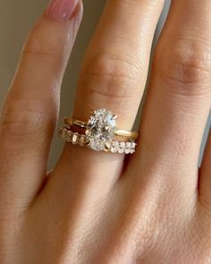 a woman's hand with a gold ring and two diamond engagement rings on it