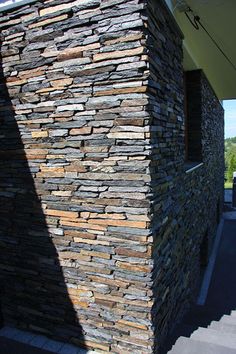 a building made out of rocks sitting on the side of a road