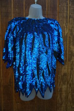 "Vintage size Medium blue and black beaded and sequined blouse. In good vintage condition.  Measurements taken across front laid flat 20\" across front armpit to armpit 25\" length 20\" across front of waist" Glamorous Blue Tops For Party Season, Glamorous Blue Sequined Tops, Festive Blue Sequined Blouse, Blue Embellished Party Blouse, Blue Sequin Top For Party Season, Festive Blue Sequin Blouse, Blue Sequin Tops For Party Season, Festive Blue Blouse With Sequins, Blue Long Sleeve Sequin Top