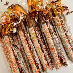 some candy sticks are wrapped in cellophane and tied with orange ribbon on top