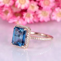 an engagement ring with a large blue stone surrounded by small white and yellow diamonds on a pink background