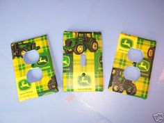 three green and yellow tractor themed light switch covers on a white surface with the words john deere printed on them