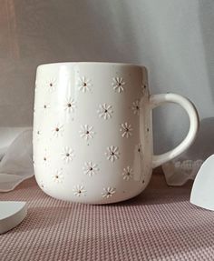 a white coffee cup sitting on top of a table next to other cups and spoons