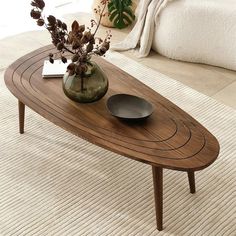 a wooden table sitting on top of a carpeted floor next to a vase filled with flowers