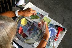 a person pouring something into a bowl on top of a newspaper