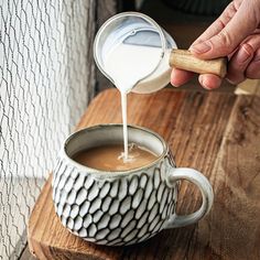 a person pours milk into a mug