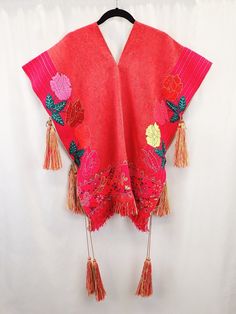 90s Chiapas poncho, handwoven Pok'u'ul, floral poncho with tassels, neon flowers and butterflies, tasseled poncho, Mexican maximalist boho Immerse yourself in the vibrant culture and craftsmanship of Chiapas with this stunning 90s Chiapas Poncho, a handwoven Pok'u'ul masterpiece. This traditional poncho, made on a pedal waist loom, embodies the rich heritage of Mexican textile artistry. Originally designed for men in Chiapas, this versatile garment now celebrates gender fluidity, allowing anyone to experience its warmth and beauty. The poncho boasts a striking color palette between red and pink, creating a bold canvas for its intricate details. Hand-embroidered neon flowers and butterflies adorn the poncho, adding bursts of vibrant color that dance across the surface. The bottom hem is acc Folk Style Festival Poncho One Size, Traditional Fringe Poncho One Size, Bohemian Embroidered Festival Poncho, Handwoven Poncho Shawl For Festivals, Handwoven Festival Poncho Shawl, Bohemian Multicolor Floral Embroidered Poncho, Bohemian Handwoven Poncho For Festival, Hippie Poncho With Tassels One Size, Hippie Tassel Poncho One Size