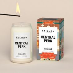 a candle that is next to a box on a table with the words friends central perk in it