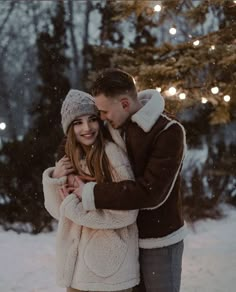 a man and woman are hugging in the snow