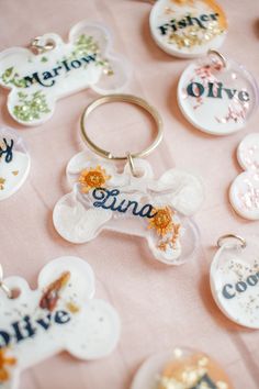 a collection of personalized dog tags on a pink tablecloth with gold glitters