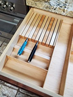 a wooden drawer with two pens in it